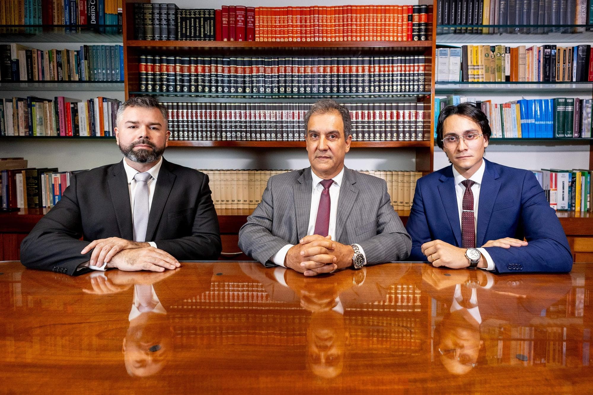 Os advogados da frente da banca à mesa da biblioteca do escritório